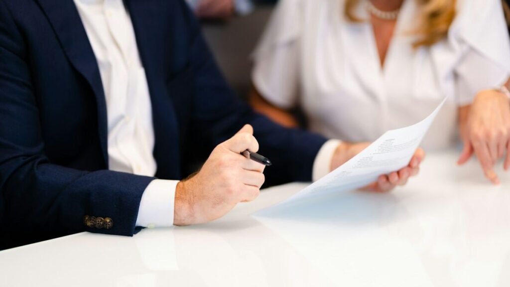 Dos profesionales revisan un documento impreso en una reunión.