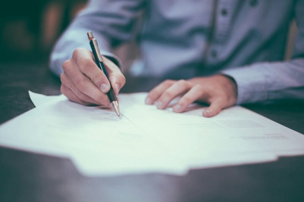 Mano escribe en un documento sobre una mesa.