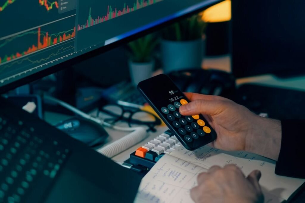 Teléfono y calculadora muestran información financiera sobre un escritorio.